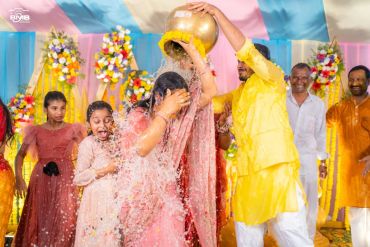 A man pours water over a woman during a festive ceremony.