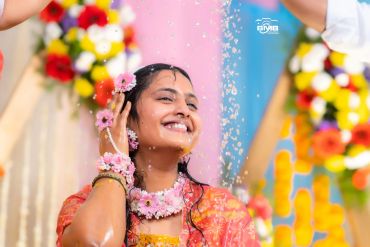 Bride smiling with flower jewelry during a ritual.