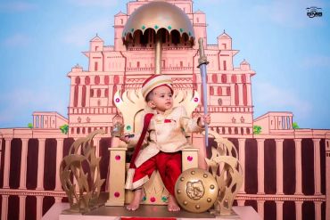 A child dressed as a royal warrior sitting on a throne.