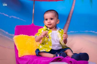 Baby sitting on a colorful chair with a bright backdrop.