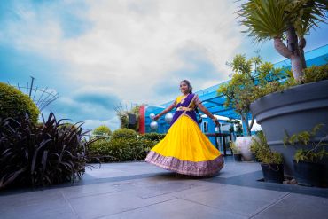 Young girl dancing outdoors in traditional attire.