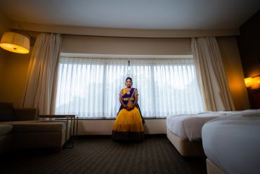 A woman in traditional attire standing by a large window in a room.