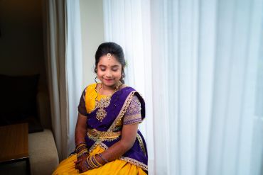 Young girl in traditional Indian attire sitting by a window.