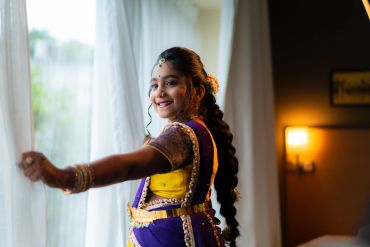 Smiling young woman in traditional attire by a window.