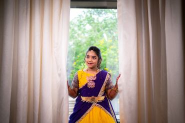 Woman in traditional dress posing between curtains.