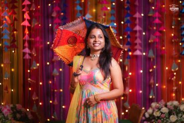 Smiling woman with a colorful umbrella at a festive event.