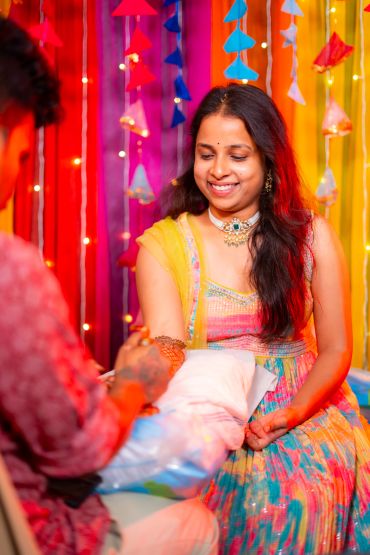 A woman smiling during henna application.