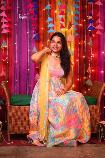 Smiling woman in colorful traditional dress at festive event.