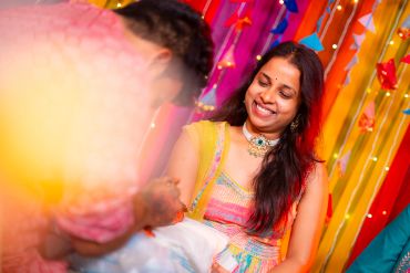 Smiling woman in traditional dress at a colorful event.