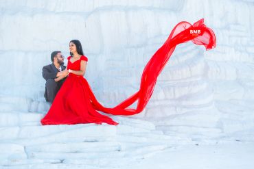 Couple in elegant attire on ice with flowing red dress.