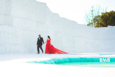 Couple walking hand in hand by a pool with snowy white backdrop.
