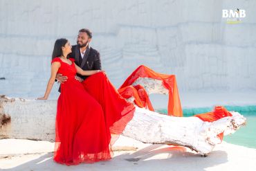 Couple posing at white sandy beach with ocean background.