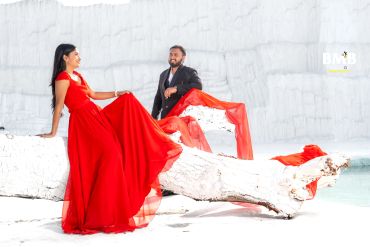 Couple posing in vibrant red and black in a white scenic backdrop.