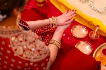 Person wearing red traditional attire with a focus on hands and jewelry.