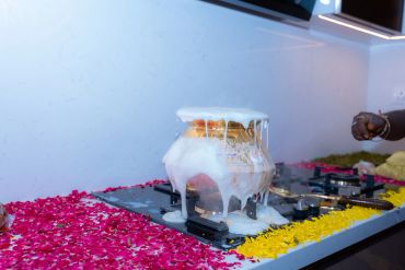 Milk boiling over in a pot on a stove decorated with flower petals.