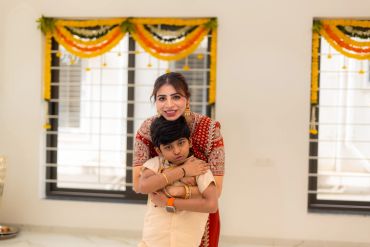 A woman hugging a boy indoors, both smiling.