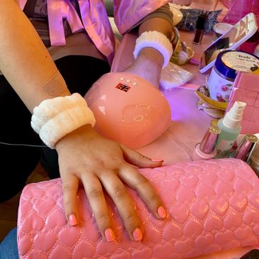 Hand with freshly painted nails drying under a UV lamp.