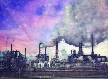 Industrial factory emitting smoke with colorful sky.
