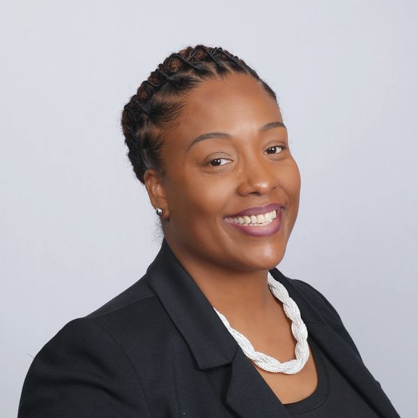 Smiling woman with braided hair and a black blazer.