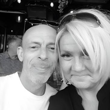 Smiling couple posing closely together indoors in black and white.