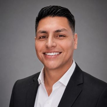 Hombre sonriendo con traje formal negro y camisa blanca.