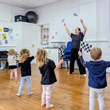Children waving checkered flags in a classroom activity.