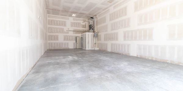 Empty unfinished room with drywall and concrete floor.