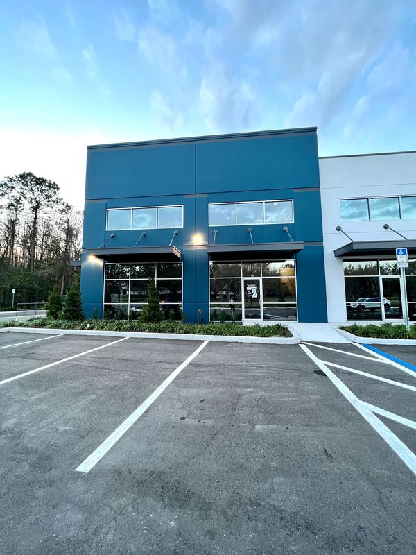 Empty parking lot in front of a modern blue office building.
