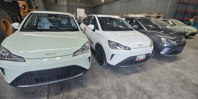 Row of parked white and gray cars in a warehouse.