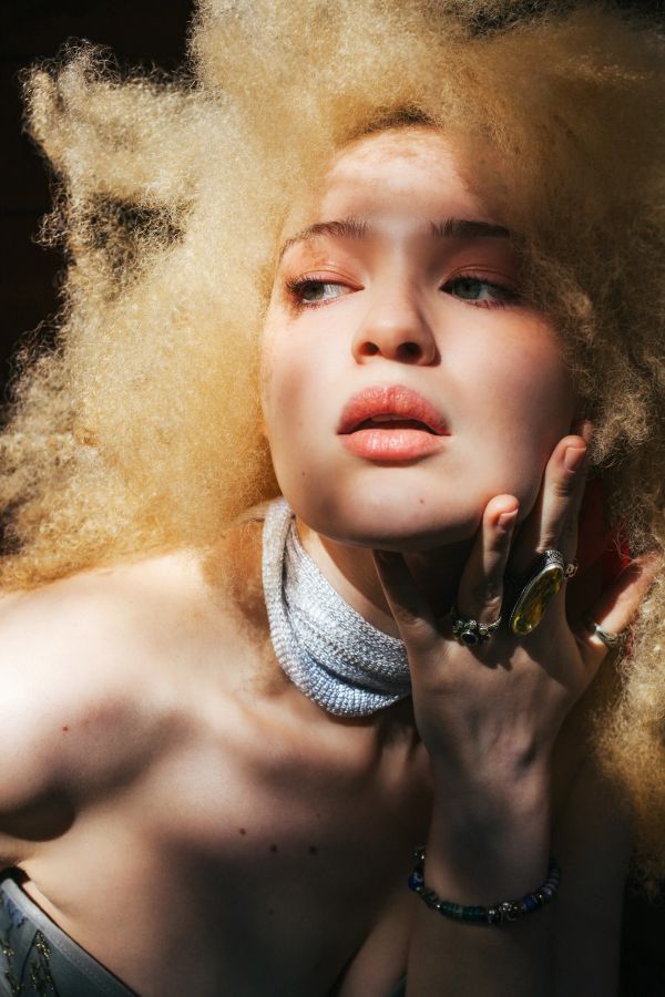 Portrait of a woman with voluminous curly hair and rings.