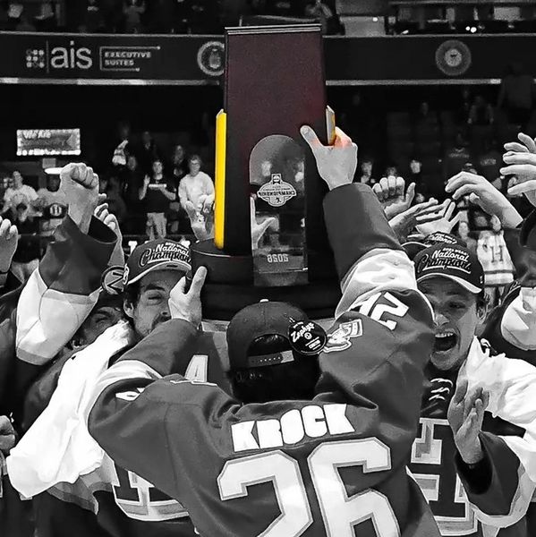 Hockey players celebrate winning the national championship, holding the trophy high.