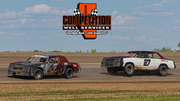 Two stock cars racing on a dirt track under a blue sky.