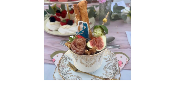 Grazing teacup with salami rose, fruit, cheese, and a Bridgerton topper for a regal touch.