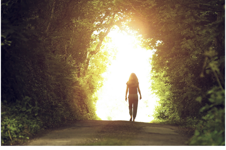 A woman walking on a path into a brightly lit future.