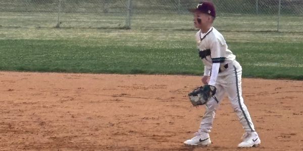 Young baseball player Dom in a ready stance on the field.