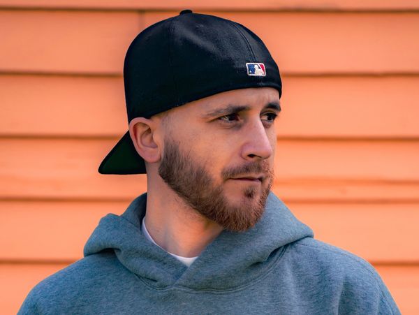Man in a black baseball cap and gray hoodie looking to the side.