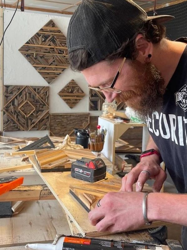 Man (Blake) crafting reclaimed barn wood geometric art at EarthTōn & Co workshop in Eden Prairie.