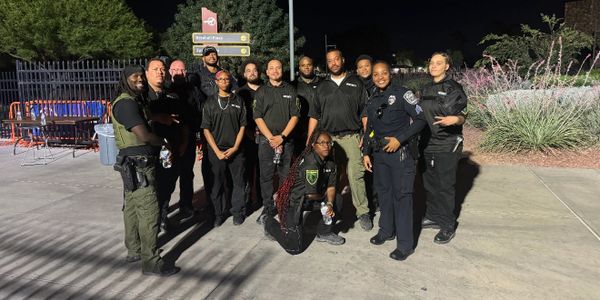 Group of security and law enforcement personnel posing outdoors at night.