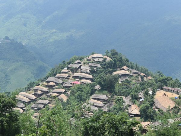 A village with thatched-roof houses nestled on a lush green hillside.