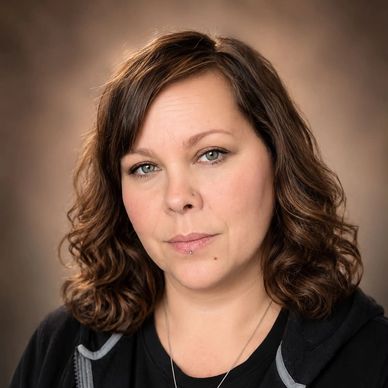 Portrait of a woman with curly hair and a neutral expression.