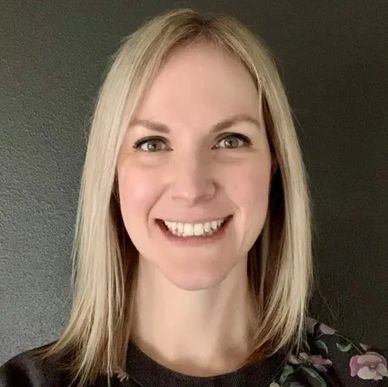 Smiling woman with blonde hair against dark background.