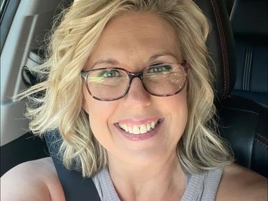Smiling woman with glasses in a car.