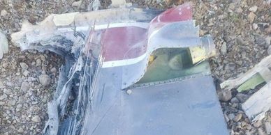 Damaged aircraft wreckage on rocky ground.