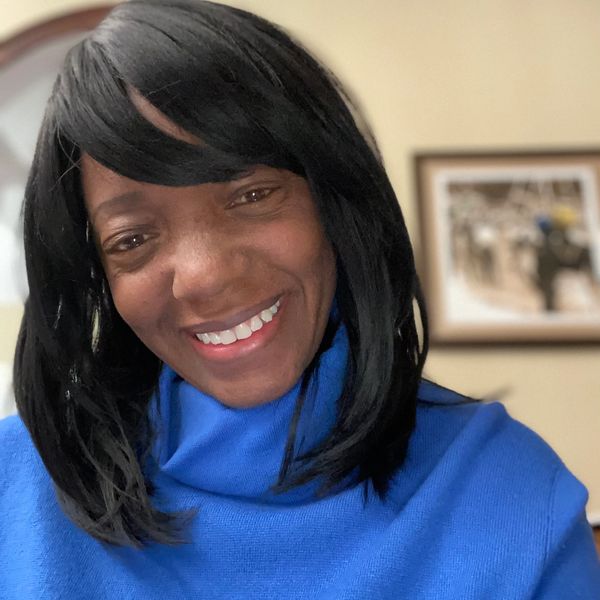 Smiling woman in a blue sweater with black hair.