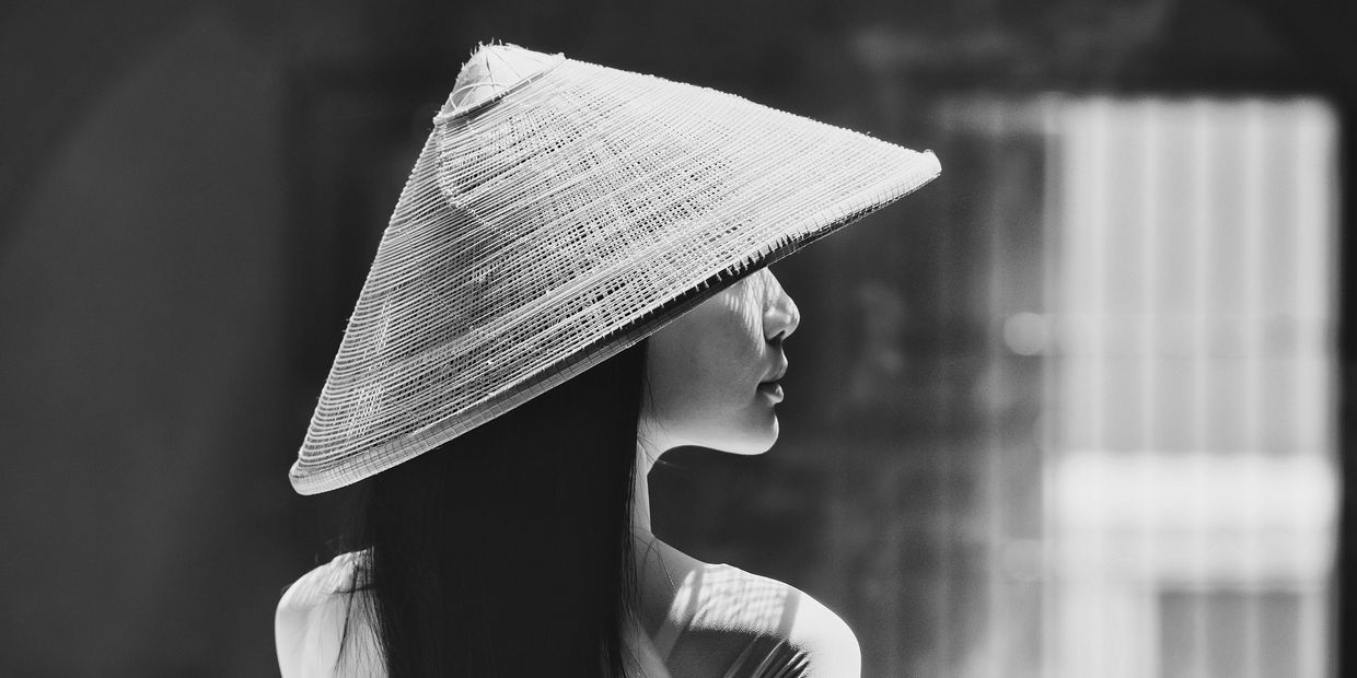 Profile of a woman wearing a traditional conical hat in black and white.