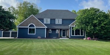 Bold blue home paint exterior with cedar shakes, white trim, and black roof DIY home remodel project