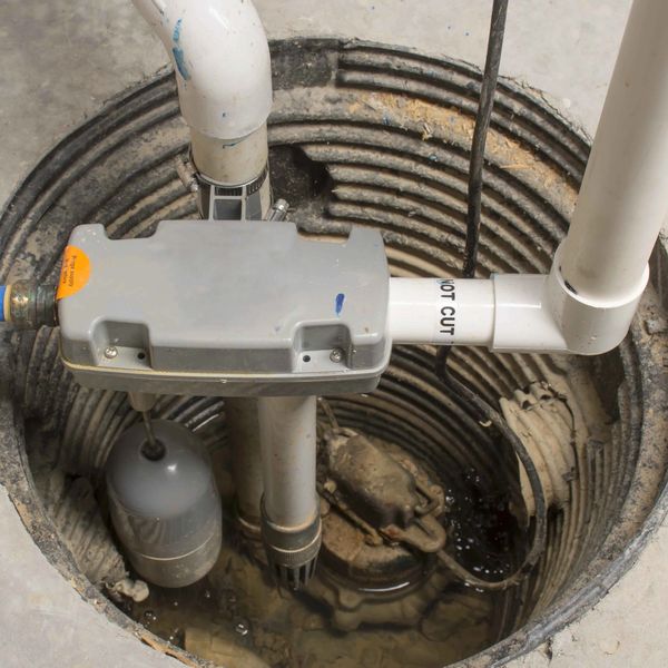 A sump pump system installed in a circular pit with PVC pipes.