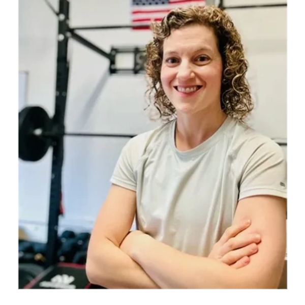 Smiling woman in gym with American flag in background.