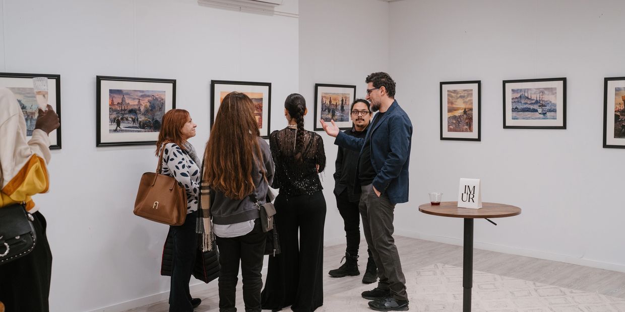People admiring and discussing paintings in an art gallery.