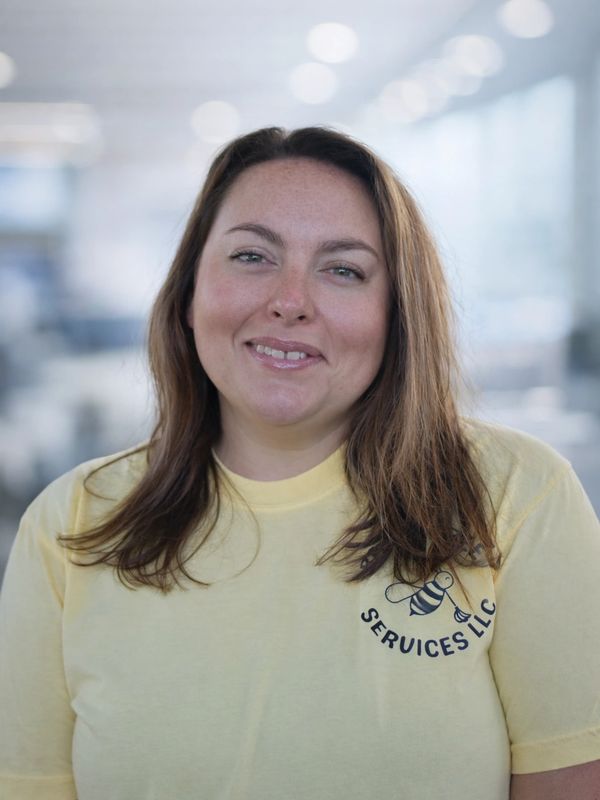 Woman in yellow t-shirt smiling in an office setting.